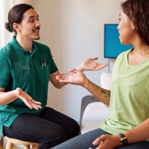 Physical therapist in a Therapeutic Rehab Specialists polo discussing treatment options with a patient