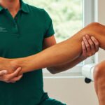 Physical therapist in a Therapeutic Rehab Specialists polo assessing a patient's knee during an evaluation